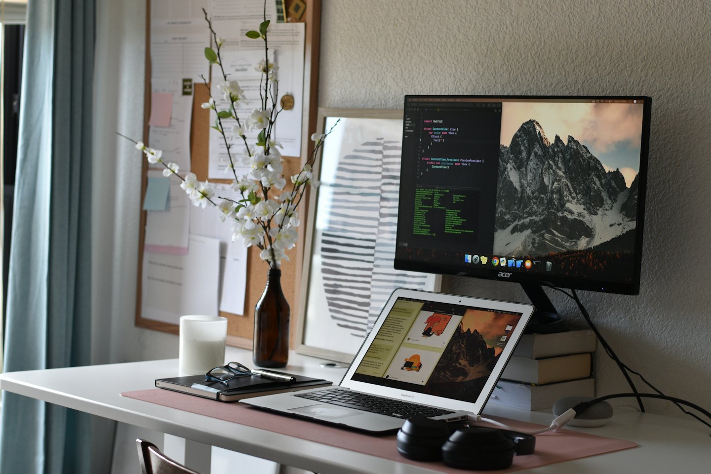 Laptop, Monitor mit Code und Kopfhörer auf einem Schreibtisch im Homeoffice.