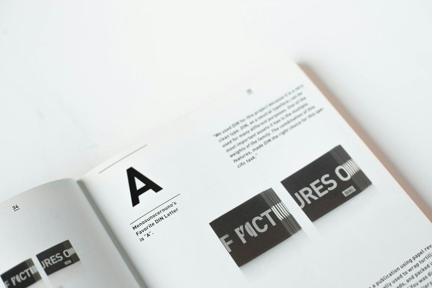 Offenes Designbuch mit Typografiebeispielen auf einem weißen Tisch.