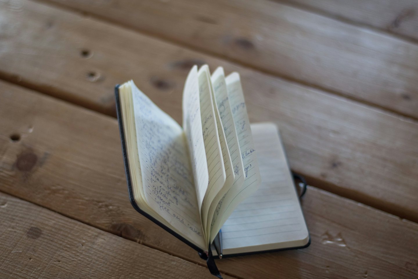 Ein offenes Notizbuch mit handschriftlichen Notizen liegt auf einem Holztisch.