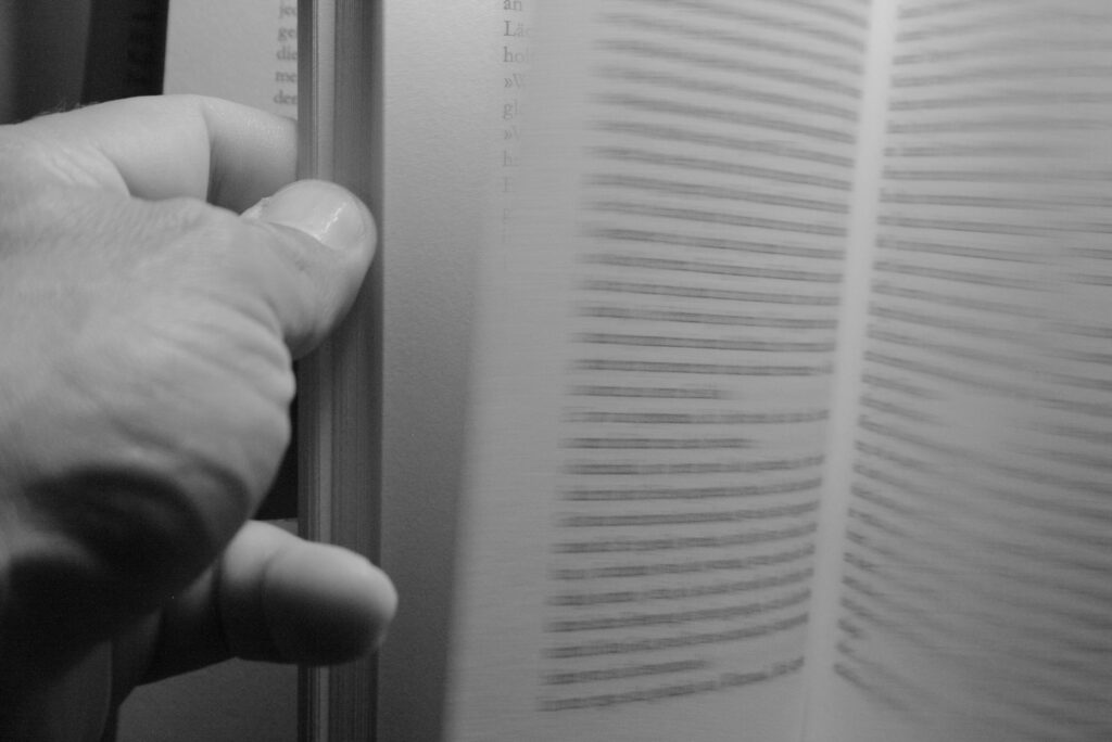 Eine Hand blättert in einem Buch.