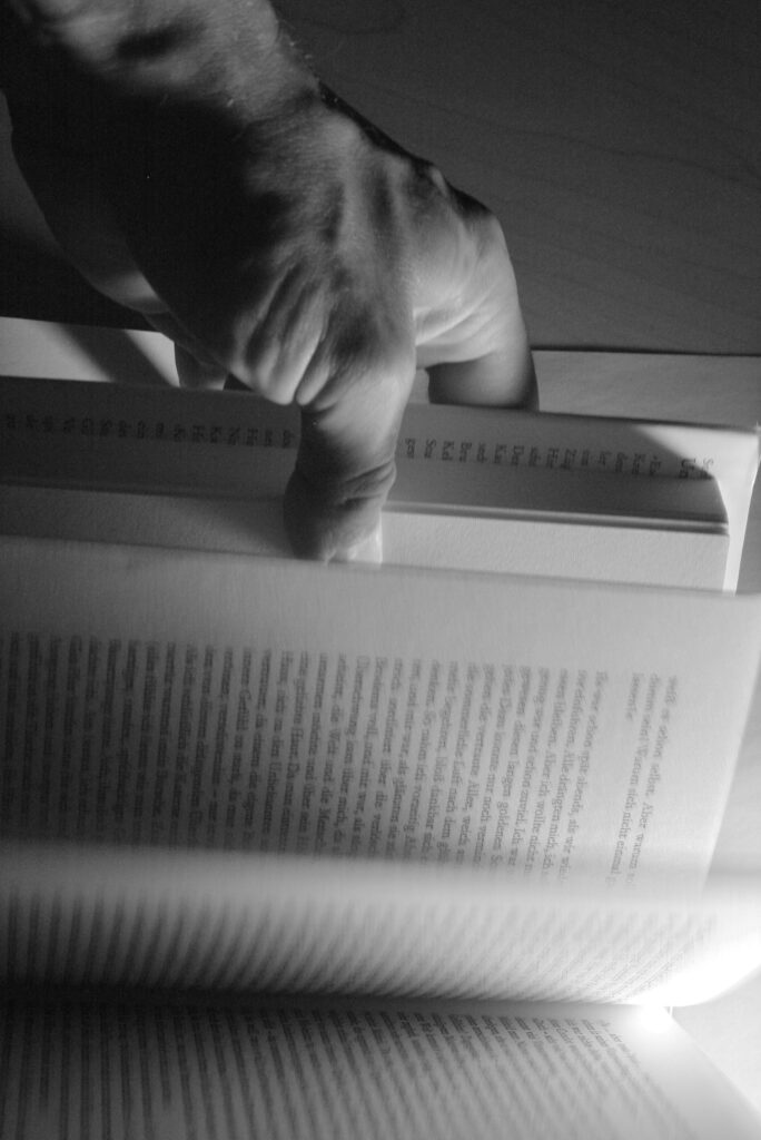 Eine Hand blättert in einem Buch.