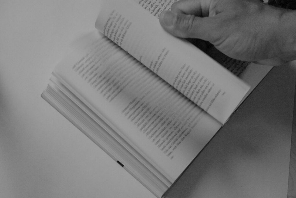 Eine Hand blättert in einem Buch.
