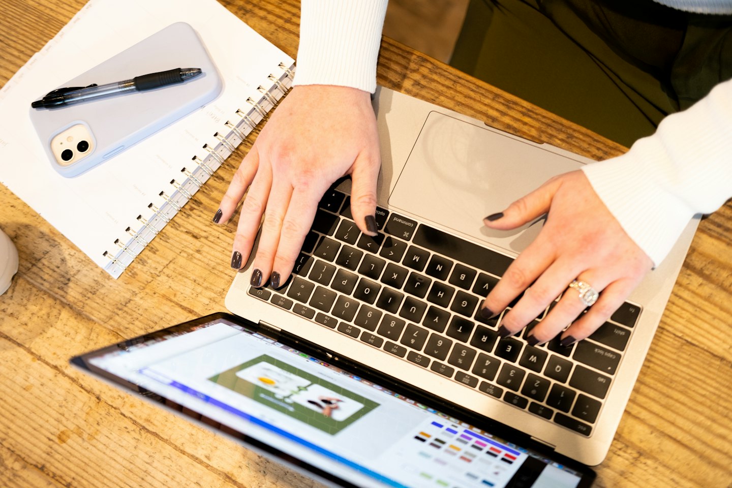 Person tippt auf einem Laptop mit geöffneter Designoberfläche.